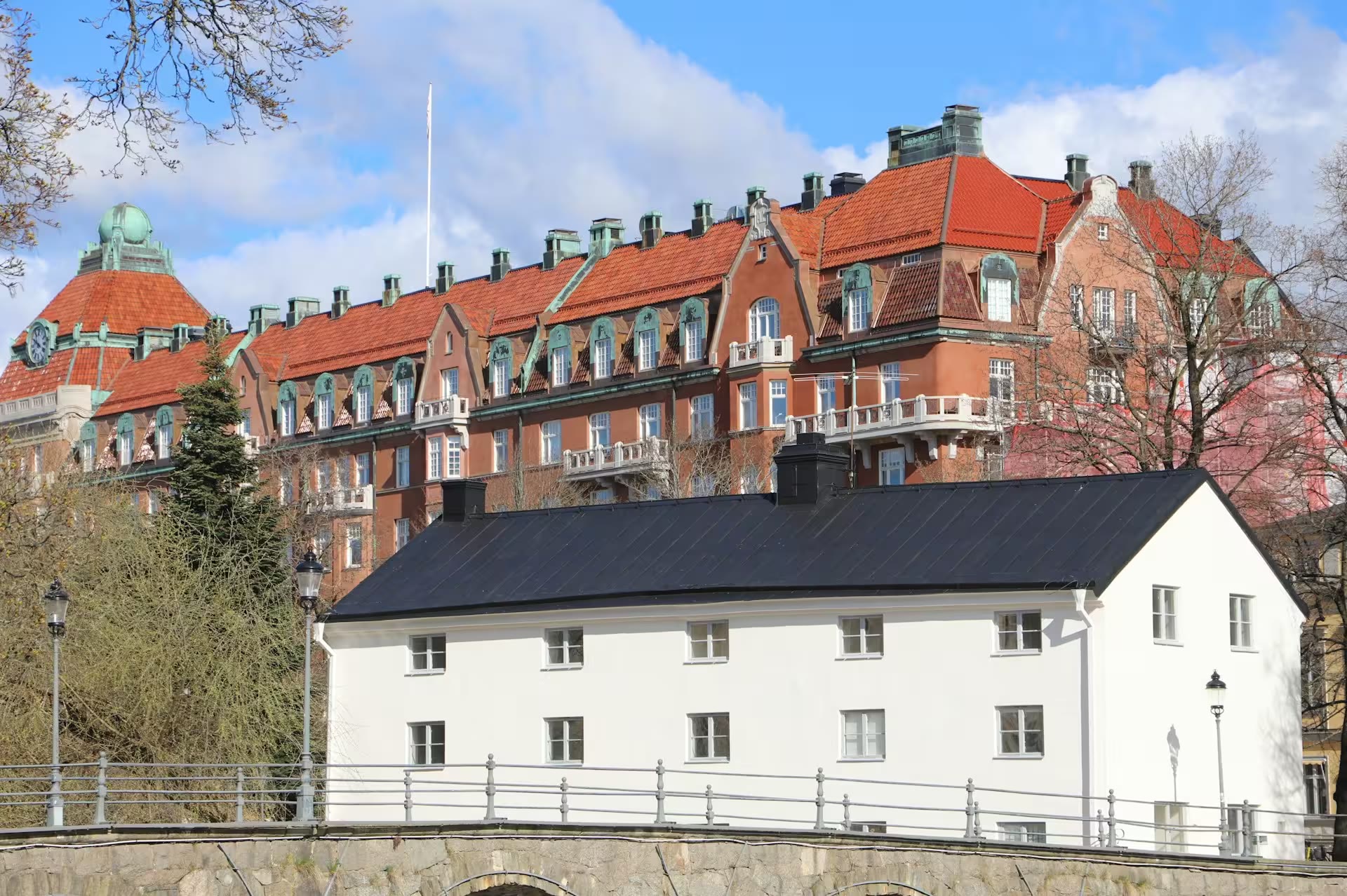 Vitt hus med svart tak framför tegelbyggnader