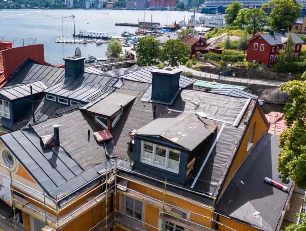 Plåttak under omläggning med ställning och utsikt över vattnet